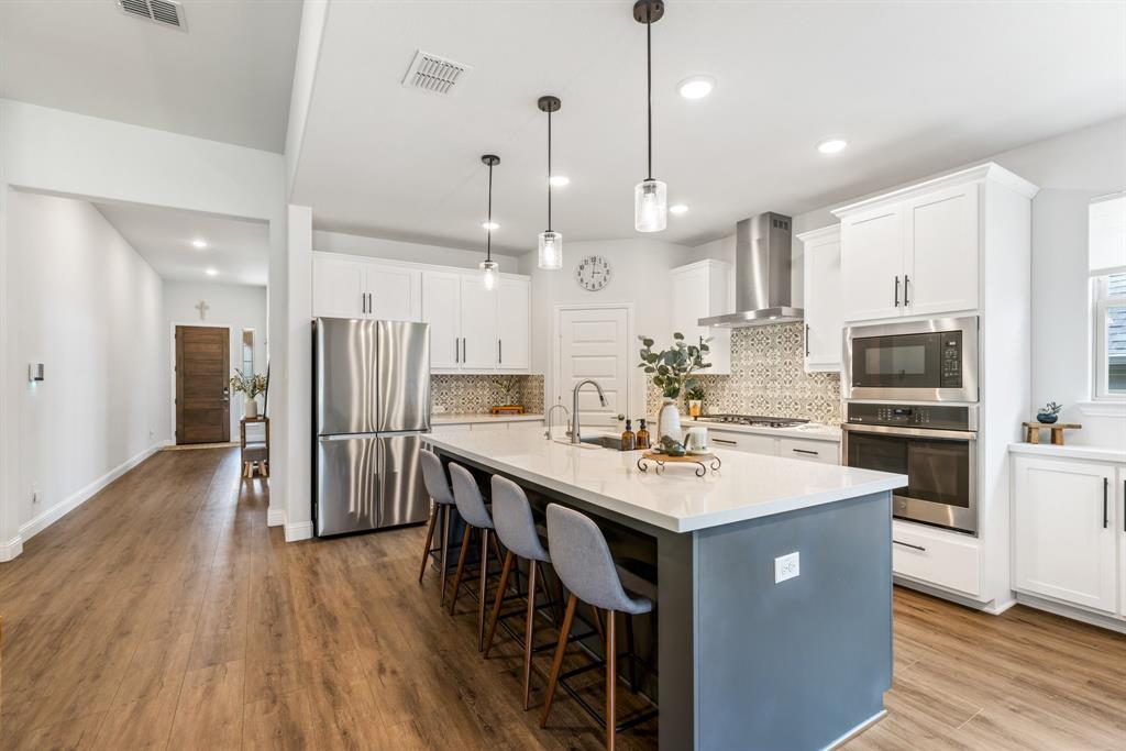 313 Savannah Lane Oak Point, TX 75068 - Photo 5 of 39 Kitchen with white cabinets, stainless steel appliances, a kitchen island with sink, hanging light fixtures, and recessed lighting