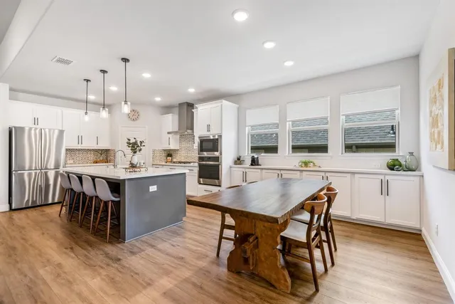 a large kitchen with stainless steel appliances a large center island and a wooden floor