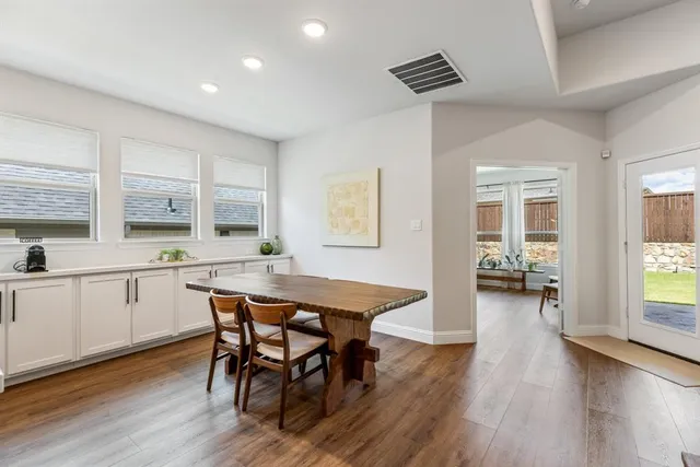 a kitchen with stainless steel appliances kitchen island granite countertop a table chairs and a refrigerator