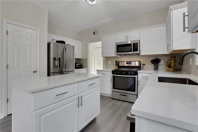a kitchen with white cabinets and stainless steel appliances