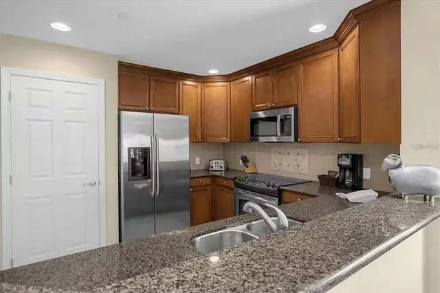a kitchen with stainless steel appliances granite countertop a sink a stove a refrigerator and a microwave