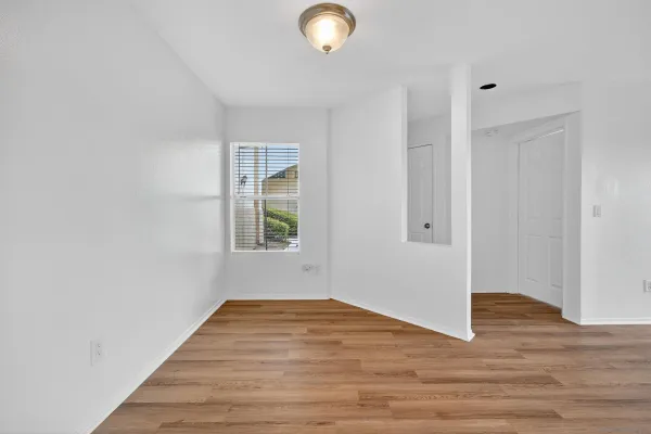 a view of an empty room with wooden floor and a window