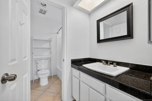 a bathroom with a granite countertop sink toilet and mirror