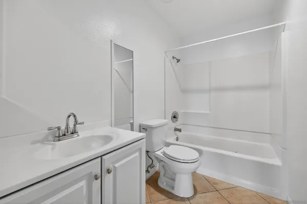 a bathroom with a bathtub shower sink vanity mirror and toilet