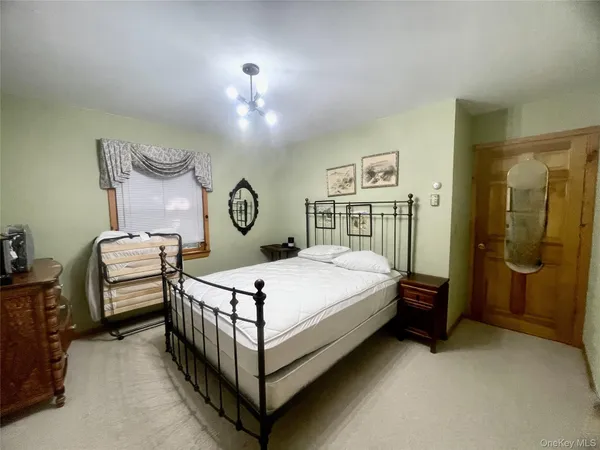 a bedroom with a bed a chandelier and dresser