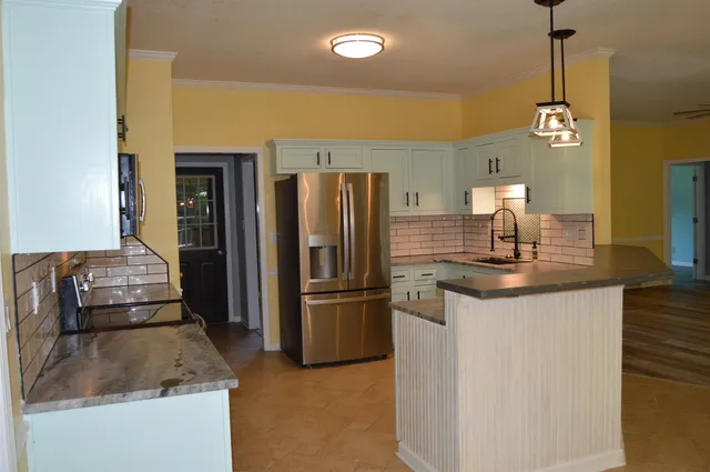 a kitchen with granite countertop a refrigerator a sink and a stove