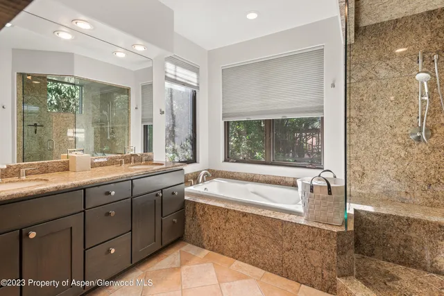 a spacious bathroom with a granite countertop sink mirror and bathtub