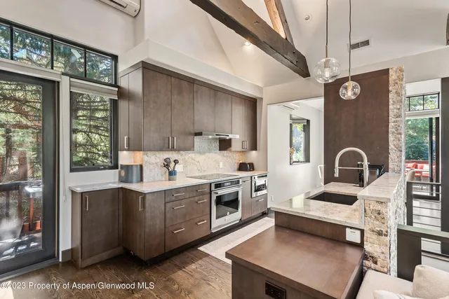 a open kitchen with stainless steel appliances granite countertop a stove top oven a sink dishwasher and white cabinets with wooden floor