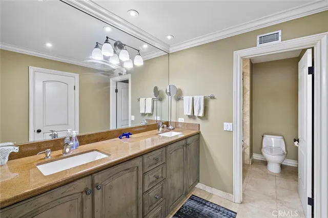 a spacious bathroom with a double vanity sink a mirror and a toilet