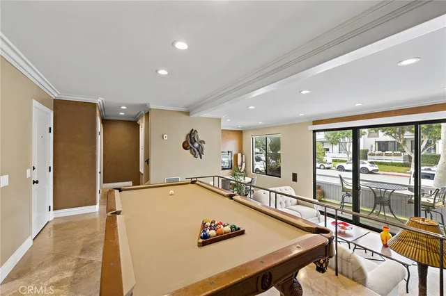 a living room with furniture pool table and large windows