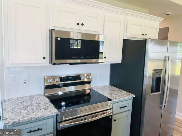 a kitchen with stainless steel appliances granite countertop a stove microwave and refrigerator
