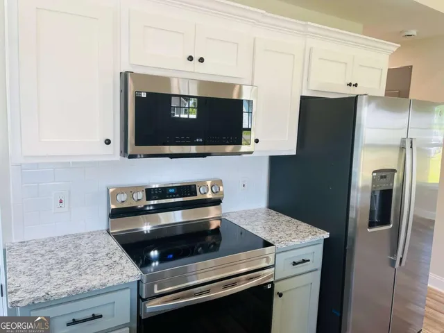 a kitchen with stainless steel appliances granite countertop a stove microwave and refrigerator