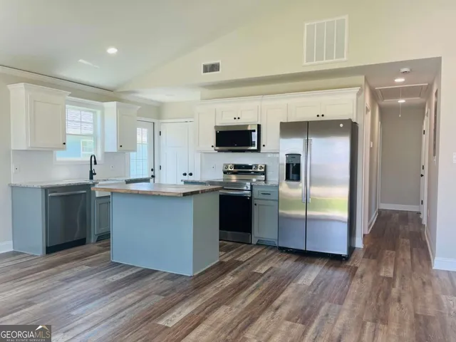 a kitchen with granite countertop a refrigerator and a stove top oven