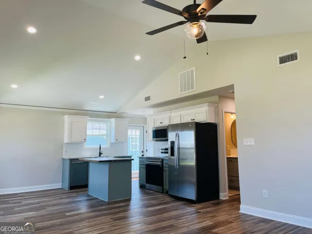 a kitchen with stainless steel appliances kitchen island a refrigerator sink and cabinets