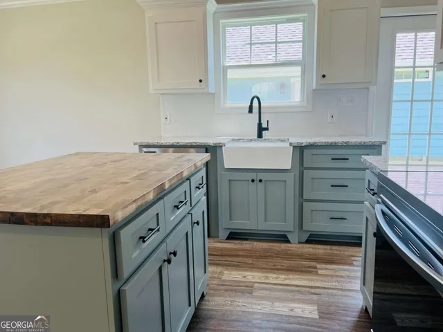 a kitchen with granite countertop a sink cabinets and a wooden floor