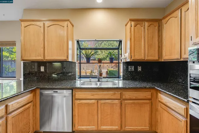 a kitchen with stainless steel appliances granite countertop a stove a sink and a microwave