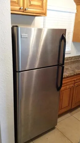 a close view of a refrigerator a kitchen island a stove a refrigerator with wooden floor