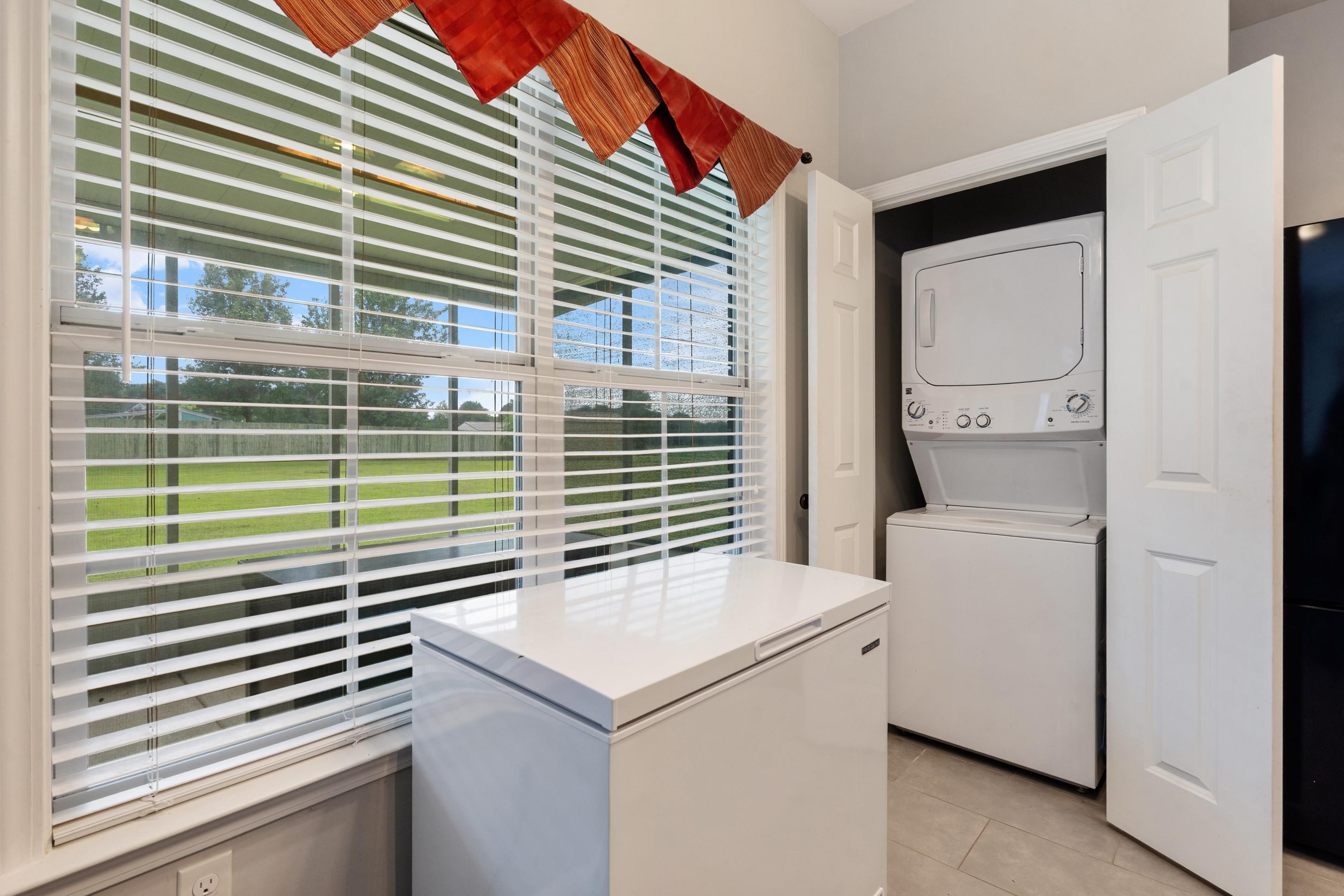 7757 Brunswick Road Millington, TN 38053 - Photo 30 of 40 Utility area featuring a built-in stacked washer and dryer, tile flooring, and a large window with horizontal blinds