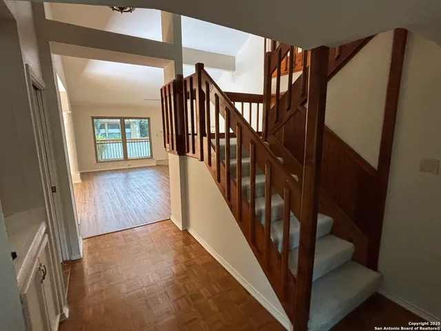 a view of staircase with lots of frames on wall and wooden floor