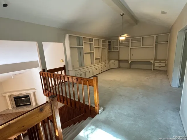 a view of an empty room with stairs and a window