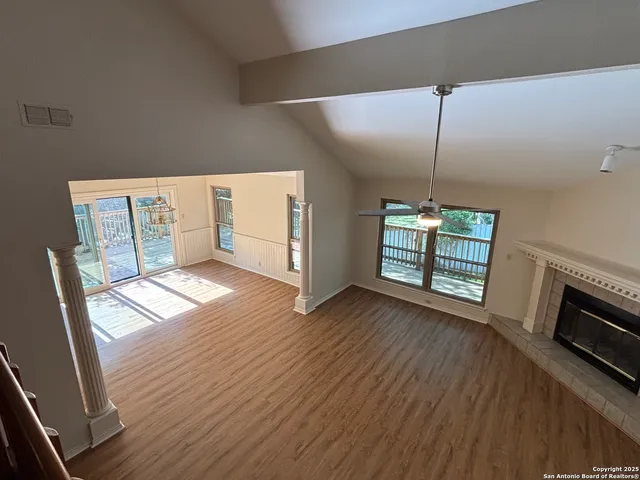 a view of an empty room with window and wooden floor