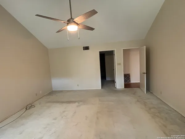 an empty room with closet and a chandelier fan