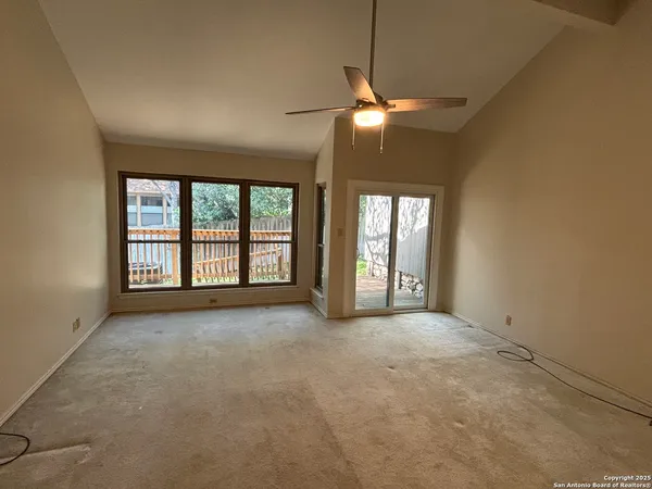 an empty room with windows and chandelier fan