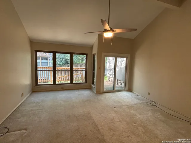 an empty room with windows and chandelier fan