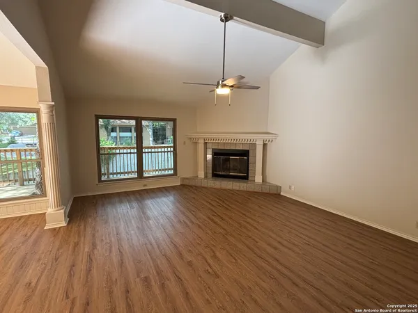 an empty room with wooden floor fireplace and windows
