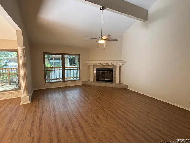 an empty room with wooden floor fireplace and windows