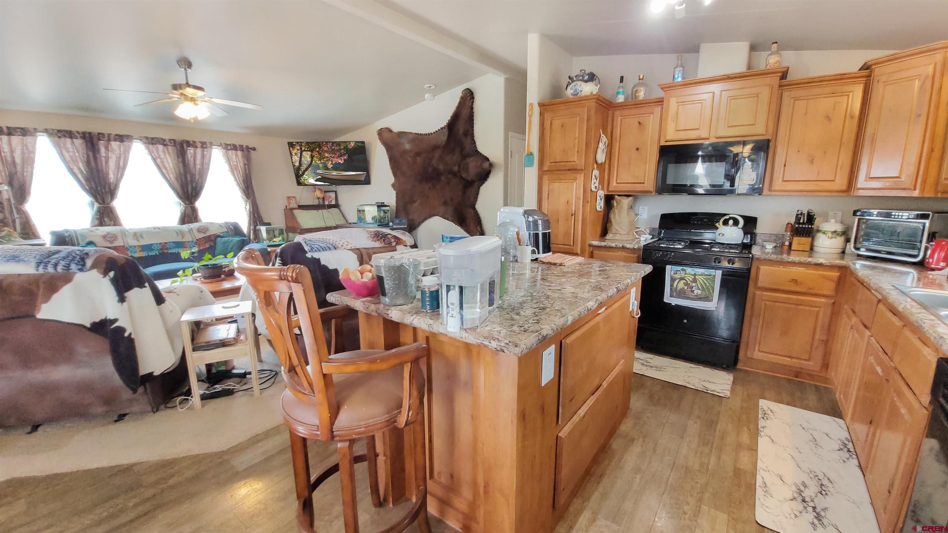 13635 County Road 23 Cortez, CO 81321 - Photo 12 of 30 a kitchen with stainless steel appliances granite countertop a stove top oven a sink dishwasher and wooden cabinets with wooden floor