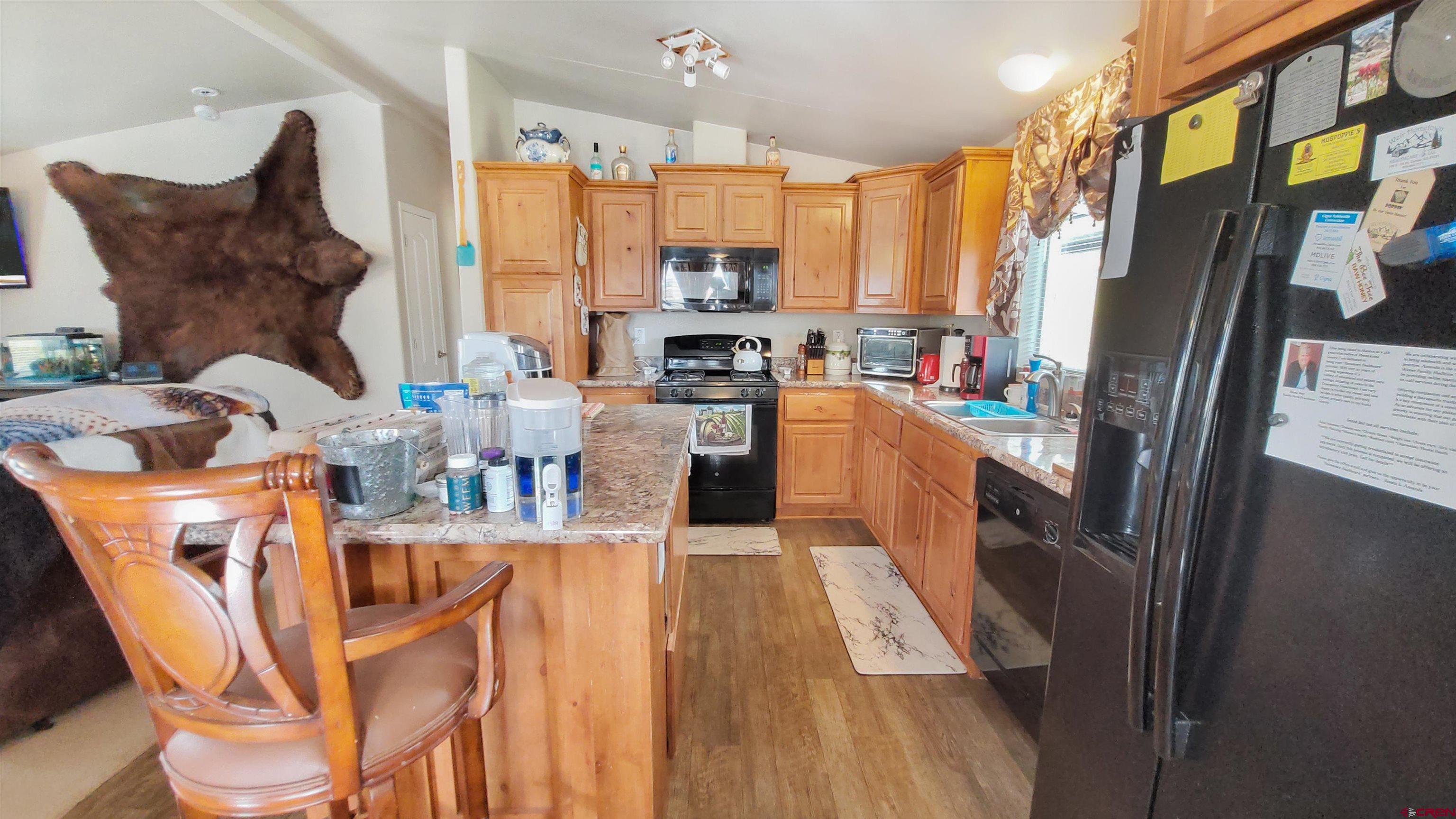 13635 County Road 23 Cortez, CO 81321 - Photo 9 of 30 a kitchen with stainless steel appliances granite countertop a refrigerator a stove top oven a sink dishwasher and wooden cabinets