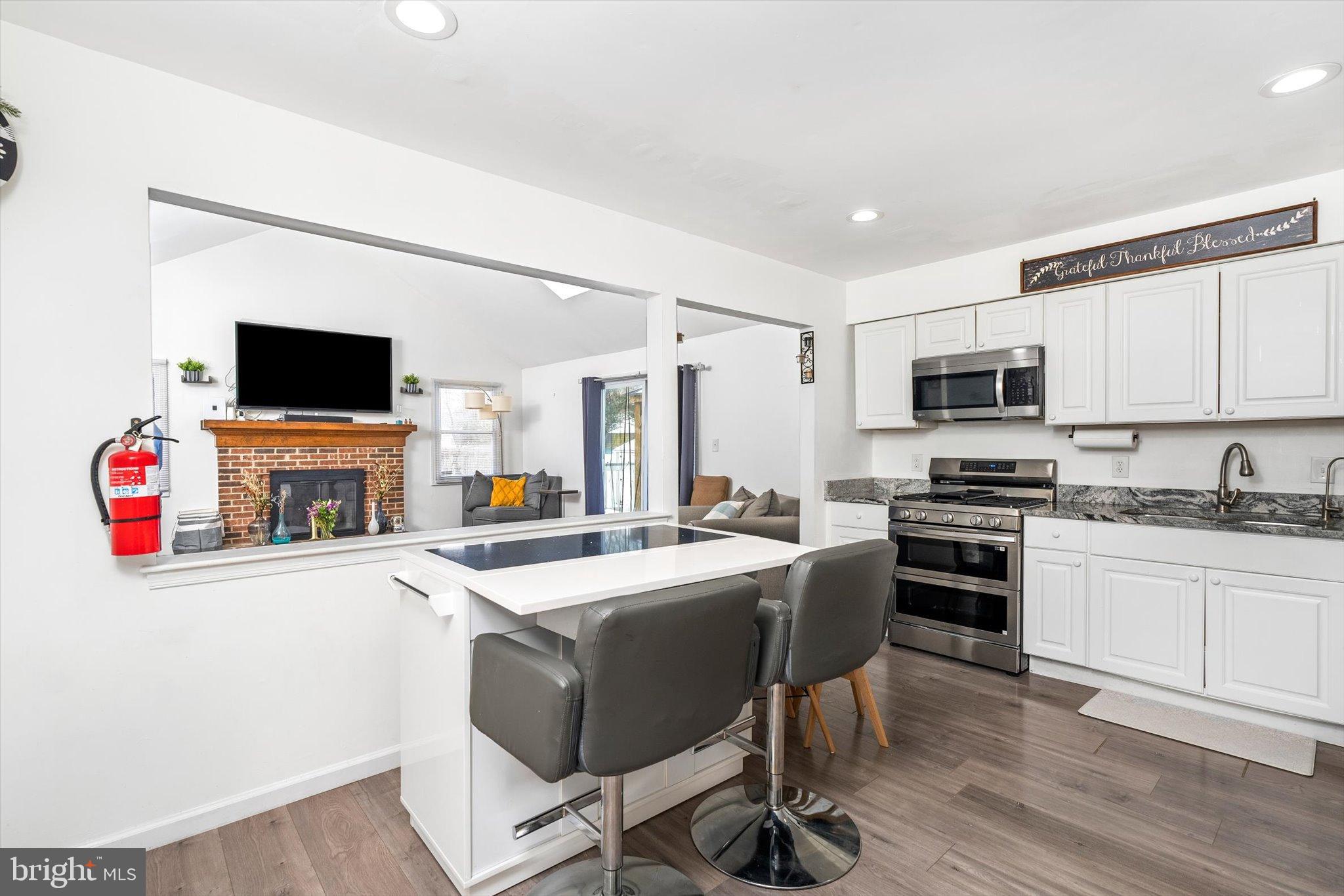 3 Scenic View Drive Sicklerville, NJ 08081 - Photo 5 of 26 a kitchen with granite countertop a stove top oven a sink dishwasher a dining table and chairs with wooden floor