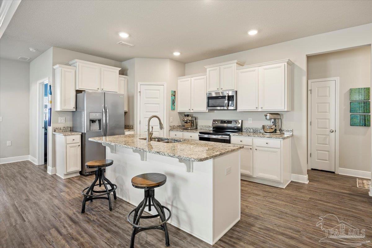 5344 Red Shoulder Road Pace, FL 32571 - Photo 14 of 28 a kitchen with stainless steel appliances granite countertop a refrigerator a stove a sink and white cabinets with wooden floor