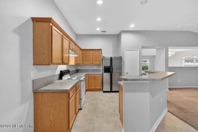 an empty room with a kitchen and a ceiling fan