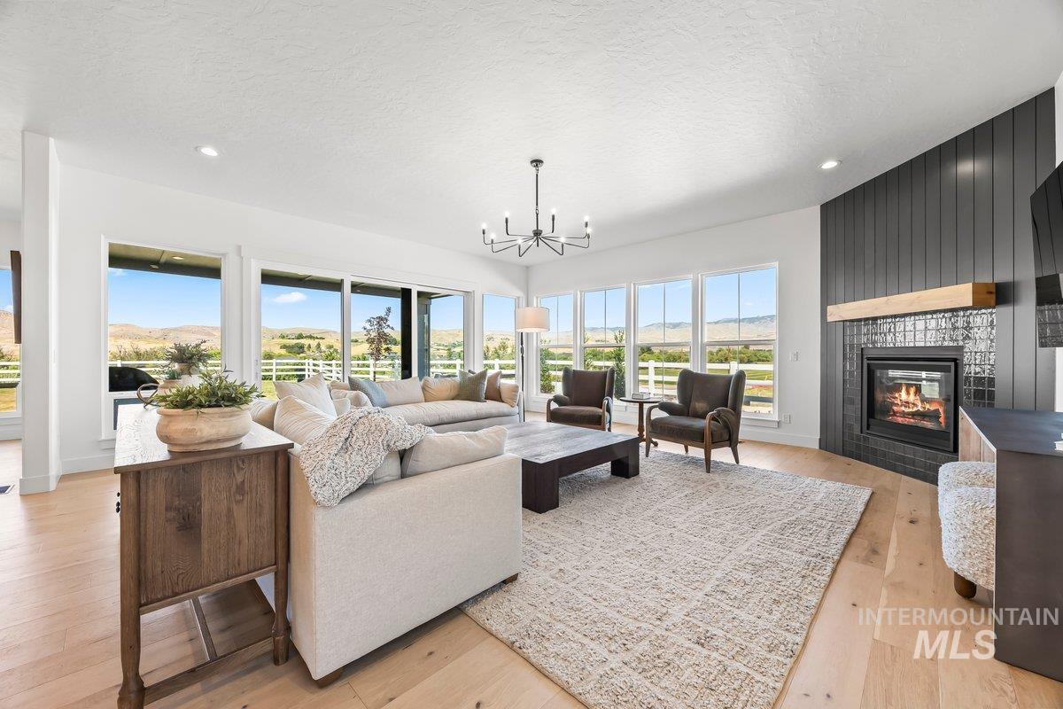 13746 North Ruffed Grouse Way Boise, ID 83714 - Photo 7 of 43 Living area featuring a chandelier, a tiled fireplace, light wood-style floors, a textured ceiling, and recessed lighting
