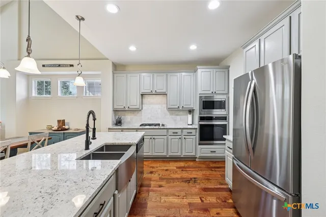 a kitchen with stainless steel appliances granite countertop a sink stove and refrigerator