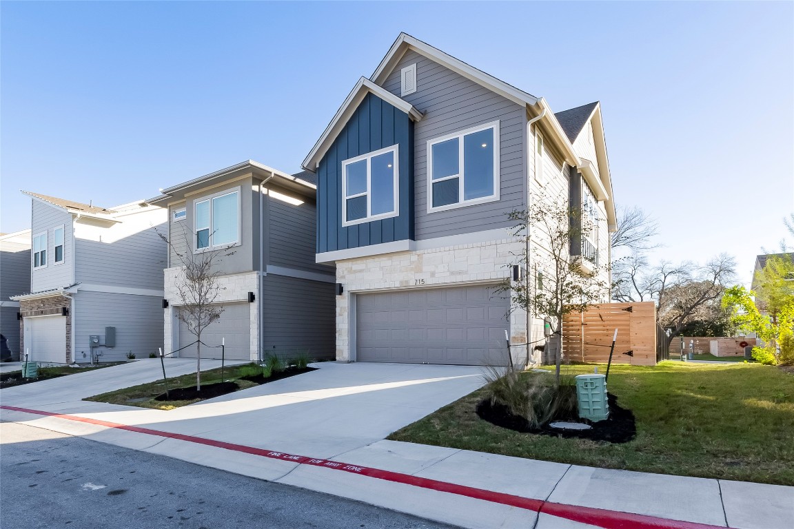 Contemporary house with driveway, stone siding, board and batten siding, a garage, and a front yard