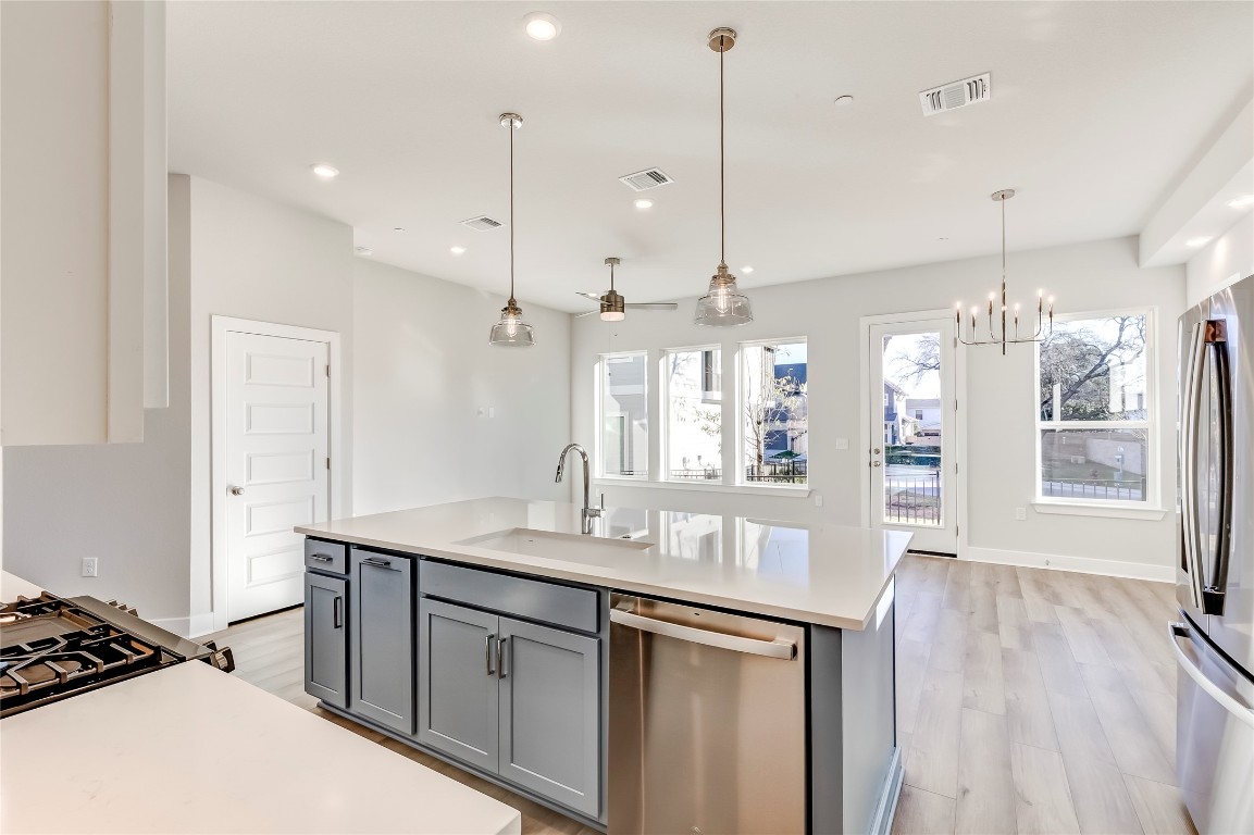 715 Bernese Pass Austin, TX 78745 - Photo 15 of 38 Kitchen with appliances with stainless steel finishes, gray cabinets, recessed lighting, hanging light fixtures, and light wood finished floors