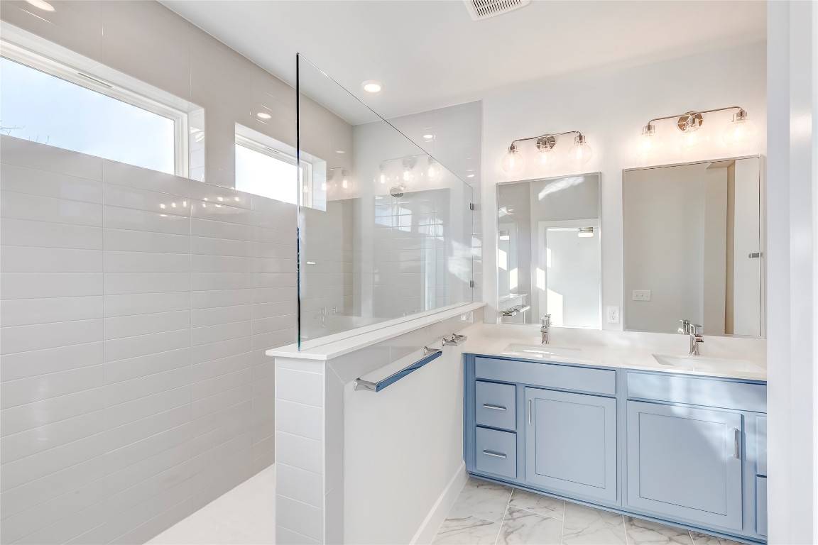 715 Bernese Pass Austin, TX 78745 - Photo 23 of 38 Bathroom with walk in shower, double vanity, and light marble finish floors