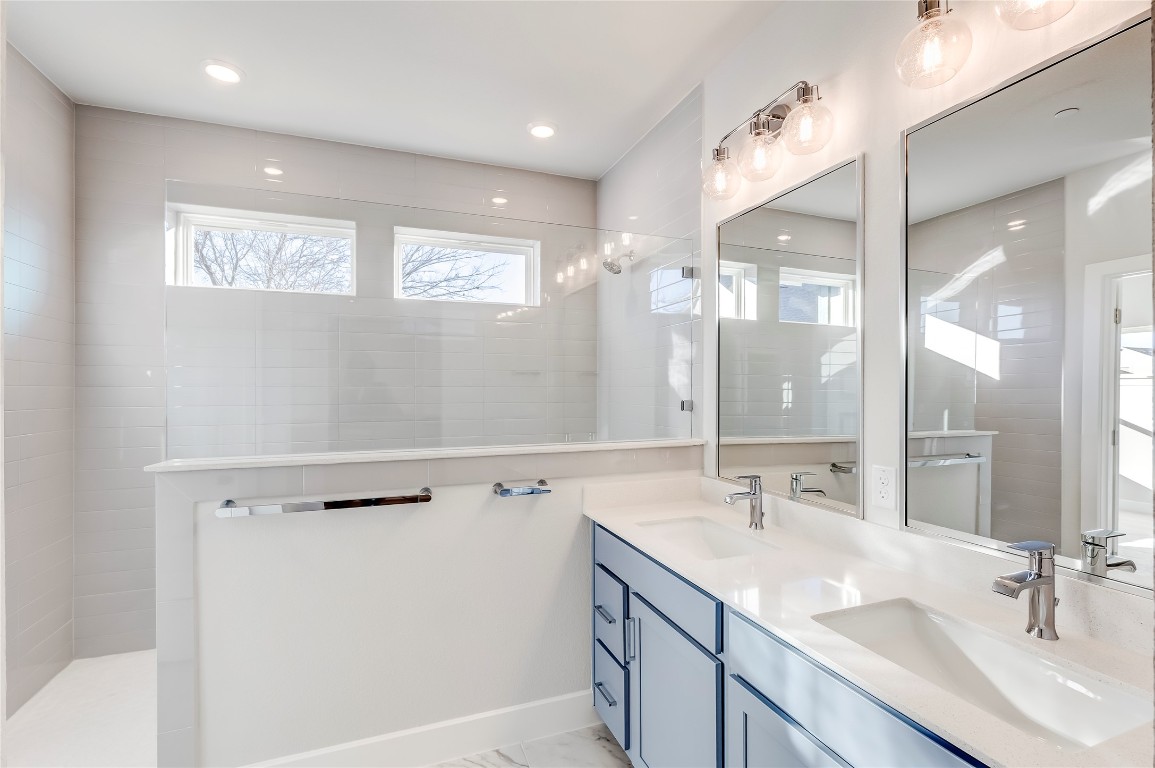 715 Bernese Pass Austin, TX 78745 - Photo 24 of 38 Bathroom with a walk in shower, double vanity, and light marble finish floors