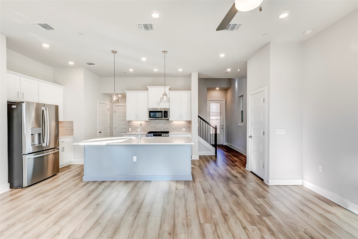 715 Bernese Pass Austin, TX 78745 - Photo 8 of 38 Kitchen featuring stainless steel appliances, white cabinets, decorative light fixtures, an island with sink, and recessed lighting