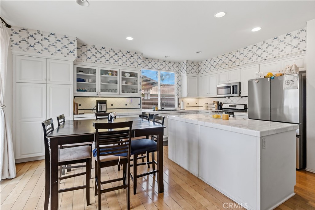 152 Alabaster Loop Perris, CA 92570 - Photo 10 of 29 a kitchen with stainless steel appliances kitchen island granite countertop a table chairs and a refrigerator