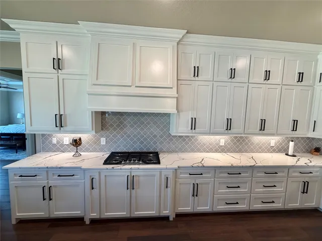 a kitchen with granite countertop white cabinets and sink