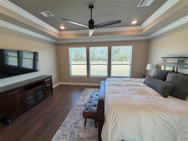 a spacious bedroom with a bed and a flat screen television