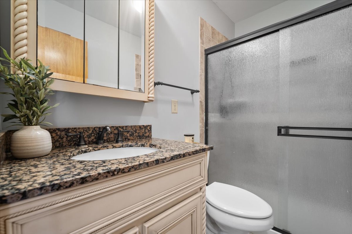 415 Bradley Lane Normal, IL 61761 - Photo 15 of 28 a bathroom with a granite countertop sink a toilet and a mirror