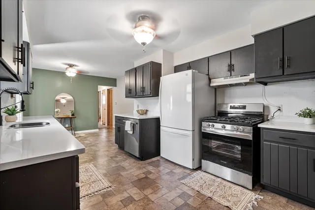 a kitchen with stainless steel appliances granite countertop a sink a stove a refrigerator cabinets and chairs