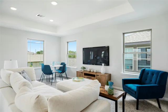 a living room with furniture a flat screen tv and a window