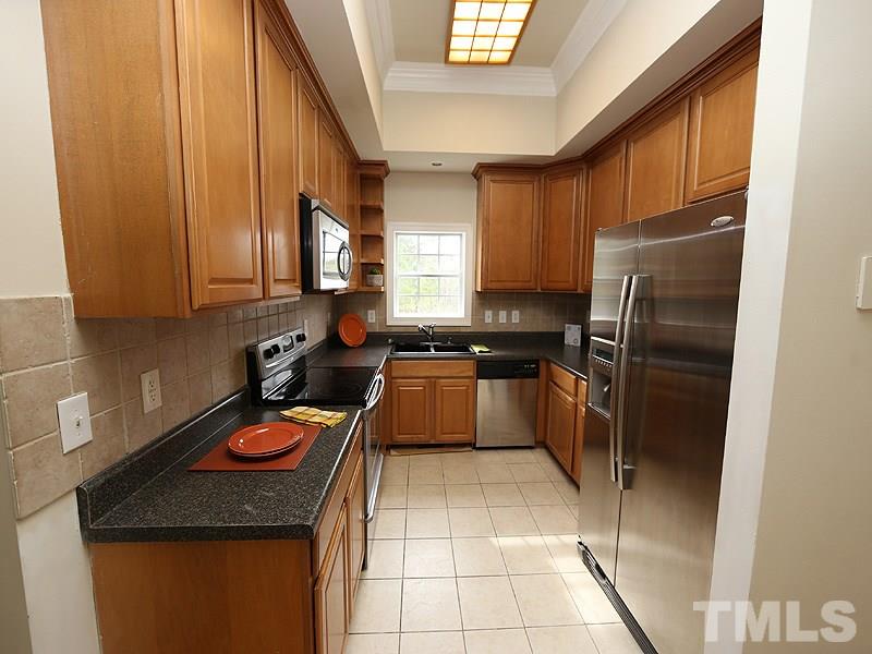 1009 Fieldgrass Place Raleigh, NC 27603 - Photo 5 of 12 a kitchen with a refrigerator a stove a sink and a window