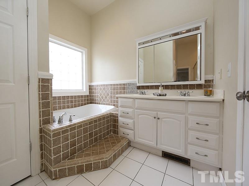 1009 Fieldgrass Place Raleigh, NC 27603 - Photo 7 of 12 a bathroom with a tub sink and mirror